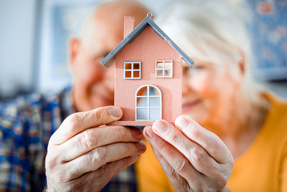 Two older people holing a model of a downsized house