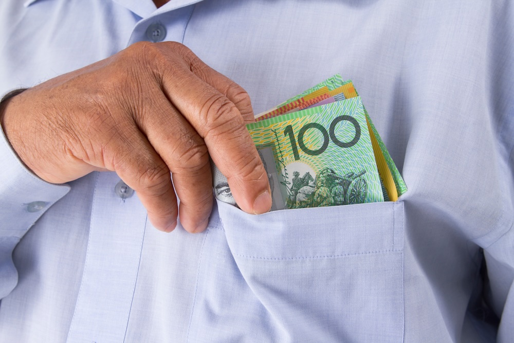 Man putting cash in his shirt pocket.