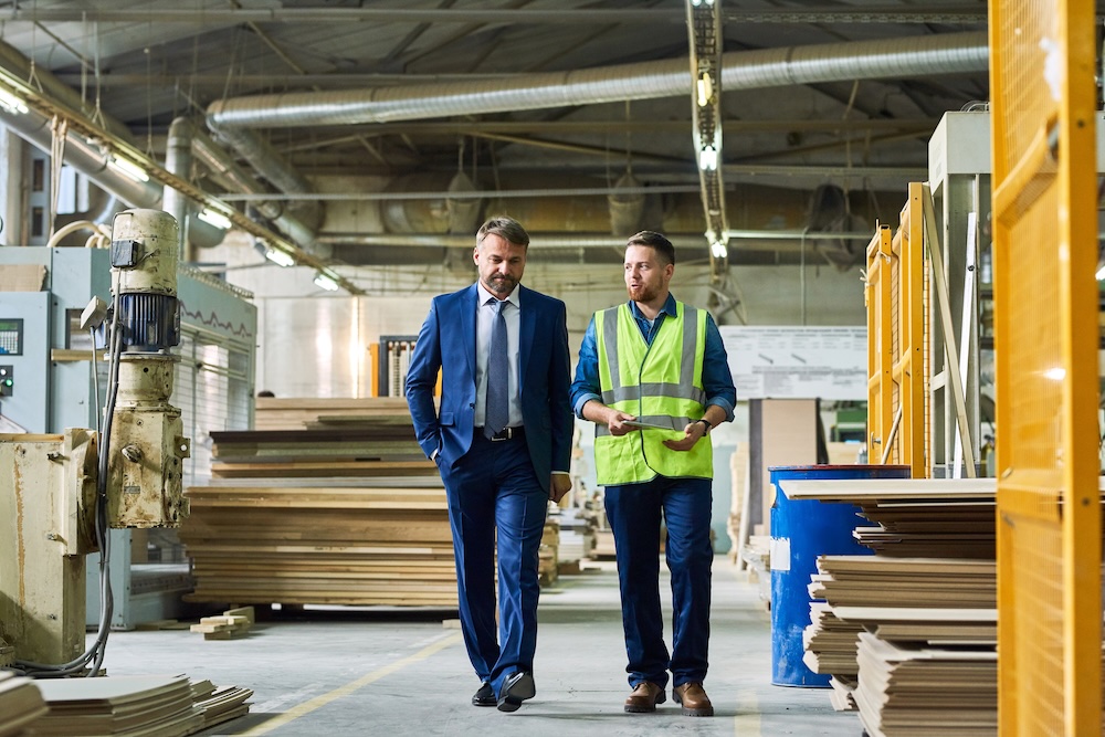 Man in suit and man in high vis walking through factory.